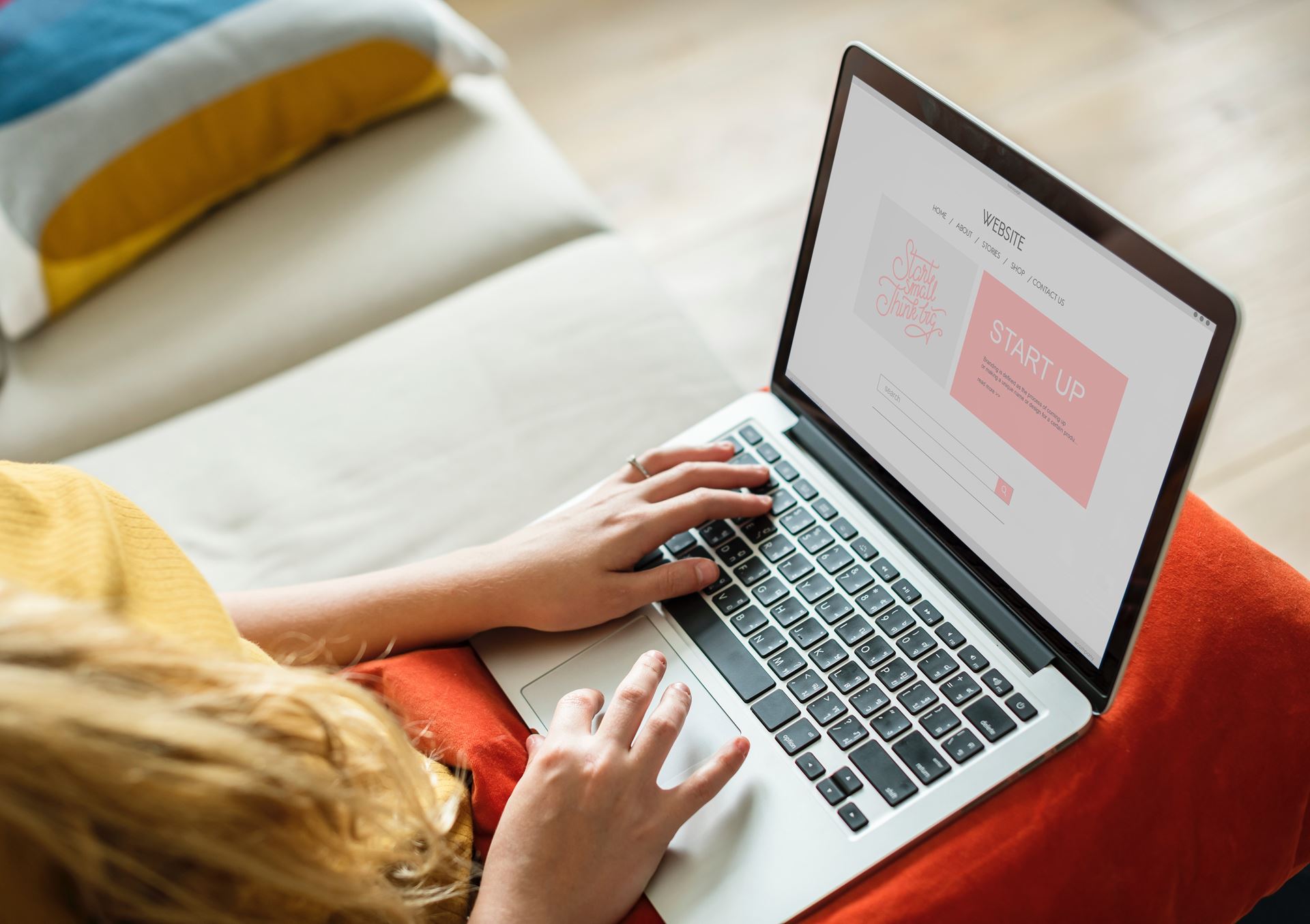 a person using a laptop computer sitting on top of a bed