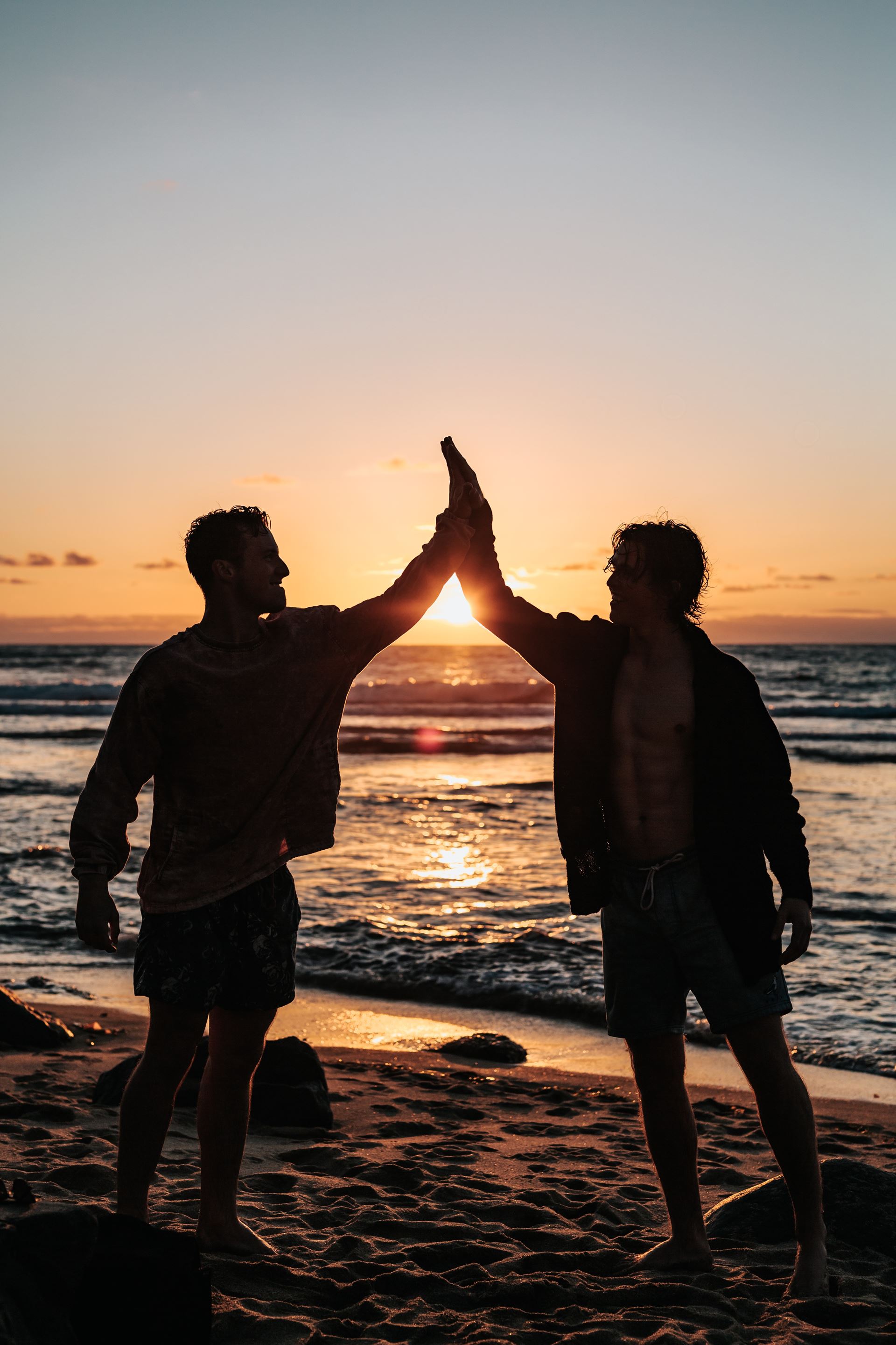 a couple of people that are standing in front of a sunset